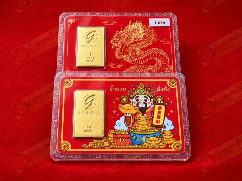 ทองคำแท่งสองแท่งที่มีป้ายระบุว่า “GCAP GOLD 1 บาท 96.5%” บรรจุในบรรจุภัณฑ์พลาสติกป้องกัน พร้อมด้วยภาพวาดมังกรและเทพเจ้าแห่งความเจริญรุ่งเรืองของจีน ซึ่งแสดงถึงทองคำแท่งคุณภาพสูง.